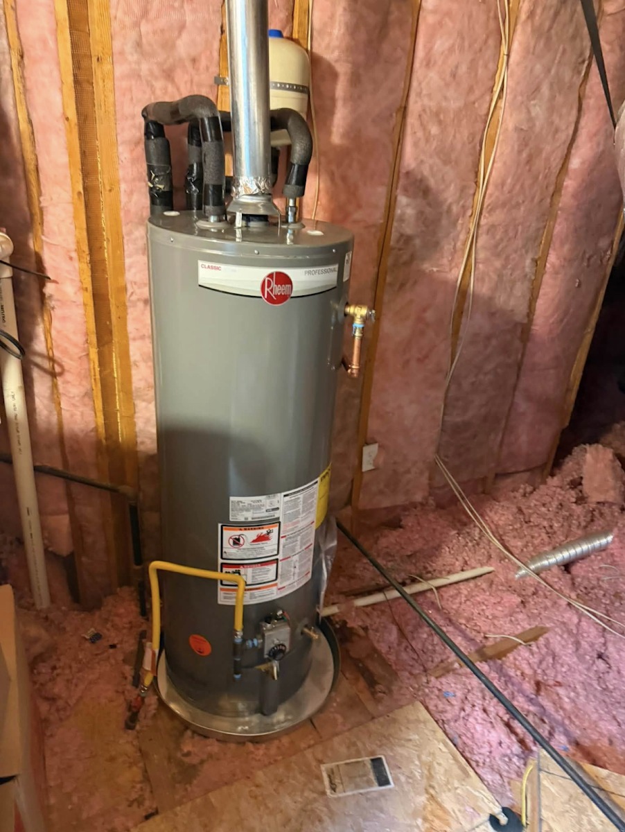 A gas tank water heater installed in an unfinished space, with flexible water connectors, a thermal expansion tank and a yellow gas connector